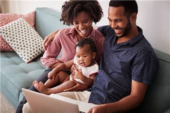 Family with baby daughter sitting in between on the sofa