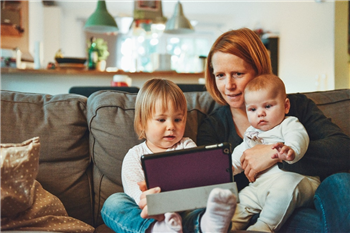 mother sitting on the sofa with two children and an ipad